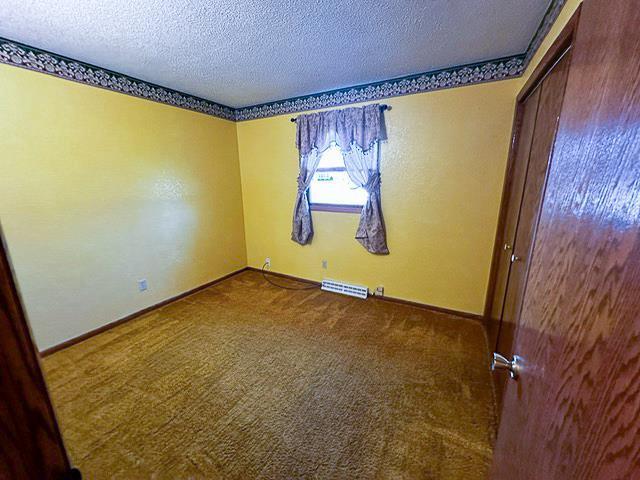 carpeted spare room featuring visible vents, a textured ceiling, and baseboards