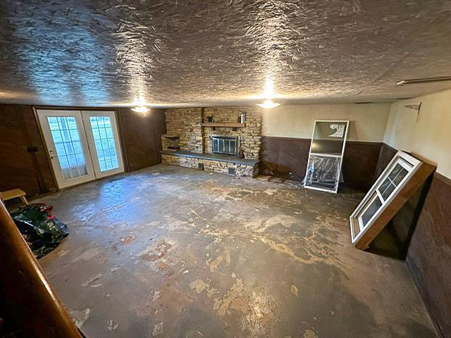 unfurnished living room featuring unfinished concrete flooring, a textured ceiling, and a stone fireplace