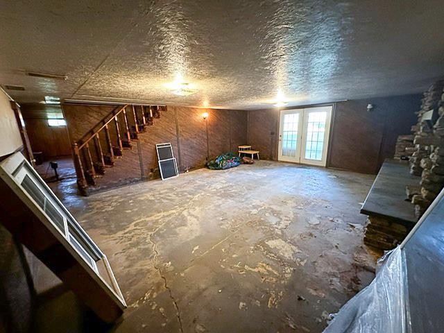 unfurnished living room featuring stairway, a textured ceiling, and concrete floors