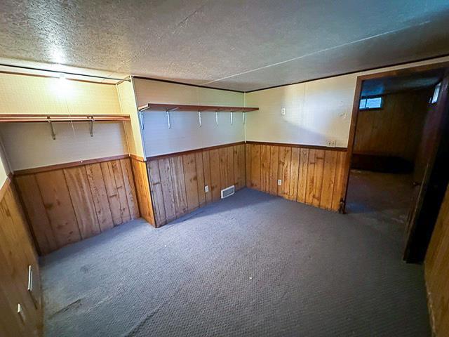 finished basement featuring a wainscoted wall, wooden walls, and visible vents