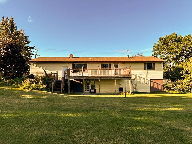 rear view of property featuring stairway, a lawn, and a wooden deck