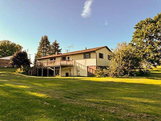 back of house featuring a yard, a deck, and stairs