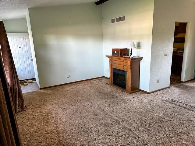 unfurnished living room with baseboards, carpet floors, visible vents, and a glass covered fireplace