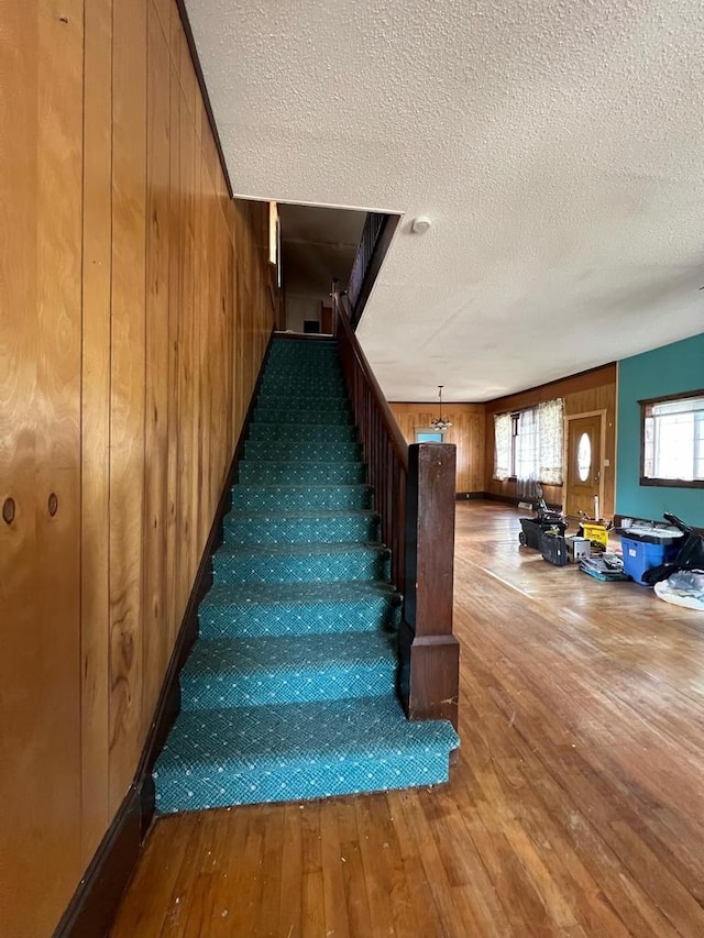 stairs featuring wood walls, a textured ceiling, and hardwood / wood-style flooring