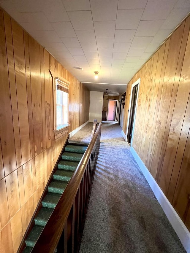 hall featuring carpet flooring and wood walls