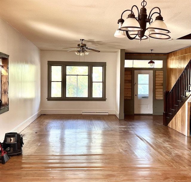 unfurnished living room with ceiling fan with notable chandelier, a textured ceiling, a baseboard radiator, and hardwood / wood-style floors