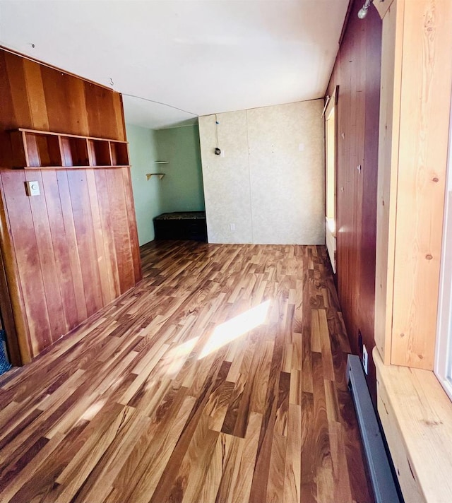 unfurnished bedroom with wood-type flooring and wooden walls