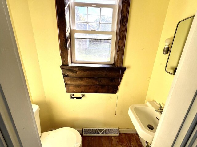 110 N Main St, Greenwood, WI 54437 - half bath featuring toilet, visible vents, a sink, and wood finished floors