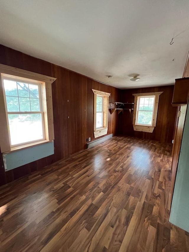 unfurnished living room with a baseboard radiator, wood walls, and dark hardwood / wood-style floors