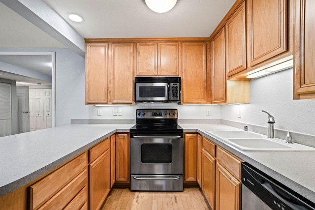 kitchen featuring stainless steel appliances, sink, and light hardwood / wood-style floors