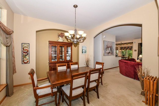 dining space featuring light carpet and a chandelier