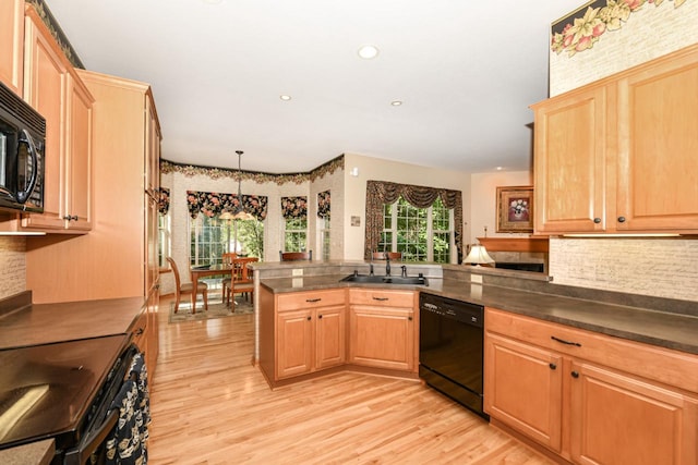 kitchen with hanging light fixtures, light hardwood / wood-style flooring, sink, black appliances, and kitchen peninsula