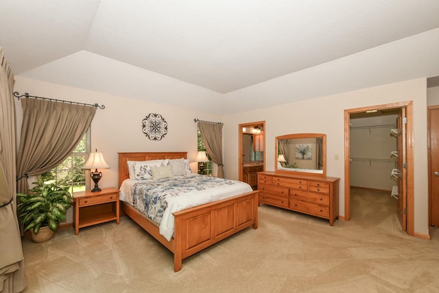 bedroom with ensuite bathroom, light colored carpet, lofted ceiling, a closet, and a spacious closet