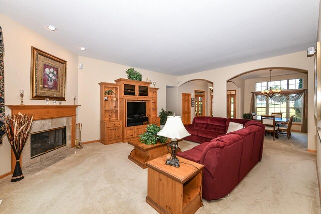 carpeted living room featuring a fireplace and a notable chandelier