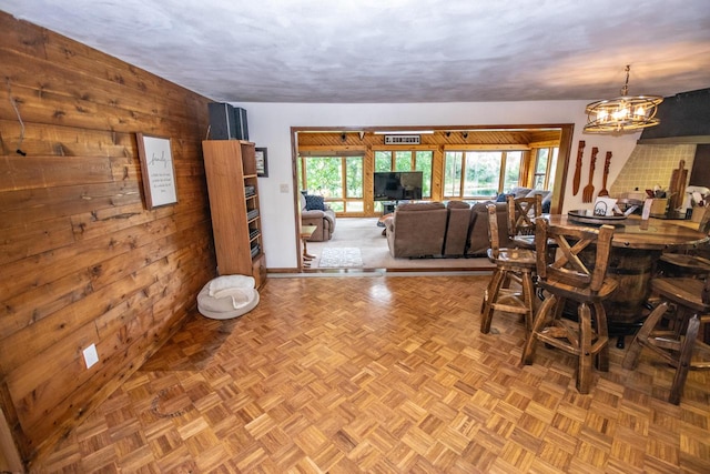 dining room featuring an inviting chandelier, wooden walls, and light parquet flooring