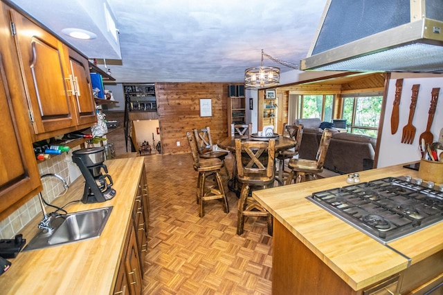 kitchen featuring stainless steel gas cooktop, wooden walls, open floor plan, and butcher block countertops