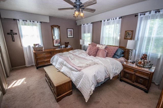 bedroom with a ceiling fan, light colored carpet, and multiple windows