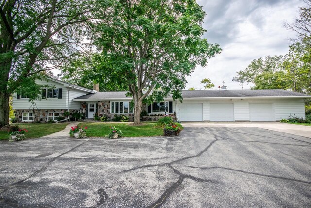 split level home featuring an attached garage, a front yard, driveway, and a chimney