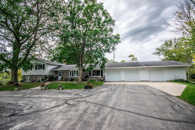 tri-level home featuring a garage, a front lawn, driveway, and a chimney
