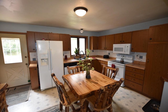 kitchen featuring decorative backsplash, white appliances, a wealth of natural light, and sink