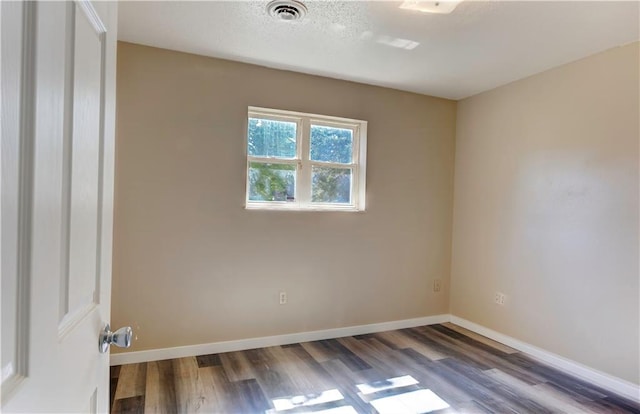 spare room with a textured ceiling and dark hardwood / wood-style floors