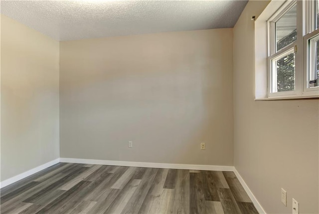 empty room with a textured ceiling and dark hardwood / wood-style flooring