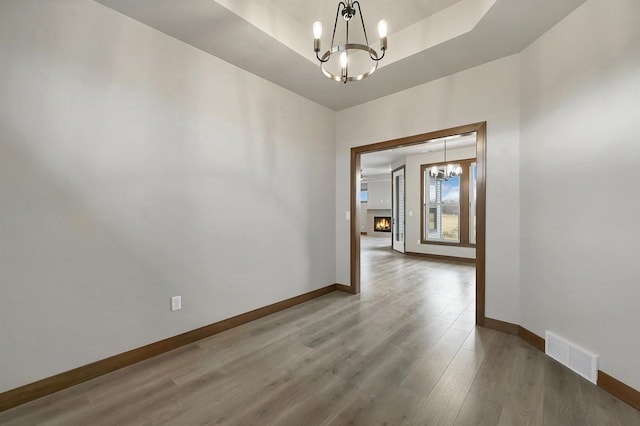1630 N Honeysuckle Cir, De Pere, WI 54115 - empty room featuring visible vents, a tray ceiling, wood finished floors, an inviting chandelier, and baseboards