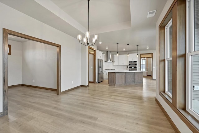 1630 N Honeysuckle Cir, De Pere, WI 54115 - unfurnished living room with baseboards, a chandelier, light wood-type flooring, a tray ceiling, and recessed lighting