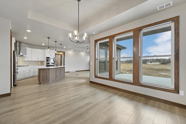 1630 N Honeysuckle Cir, De Pere, WI 54115 - kitchen with visible vents, a tray ceiling, wall chimney exhaust hood, white cabinets, and light countertops