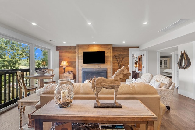 living room with wooden walls, a fireplace, and light hardwood / wood-style flooring