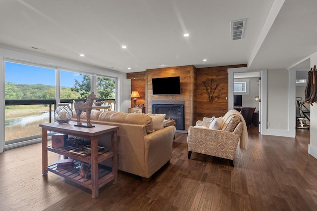 living room with hardwood / wood-style floors, wooden walls, and a fireplace