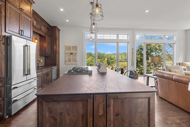 kitchen featuring dark wood-type flooring, a kitchen island, a breakfast bar area, and high quality fridge