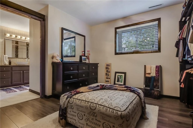 bedroom with sink, connected bathroom, and hardwood / wood-style floors