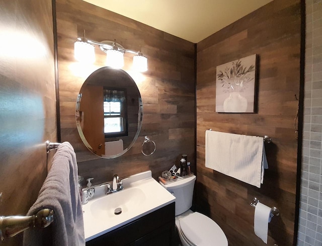 bathroom featuring tile walls, wooden walls, vanity, and toilet