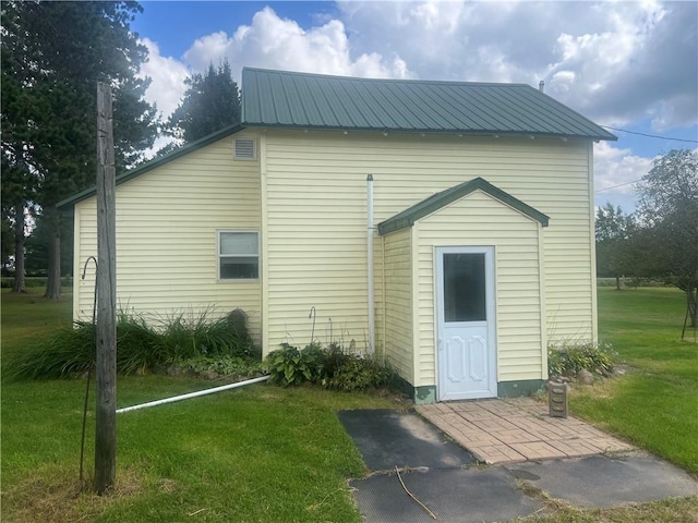 back of property featuring metal roof and a yard