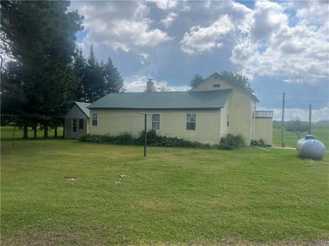 view of side of home with metal roof and a yard