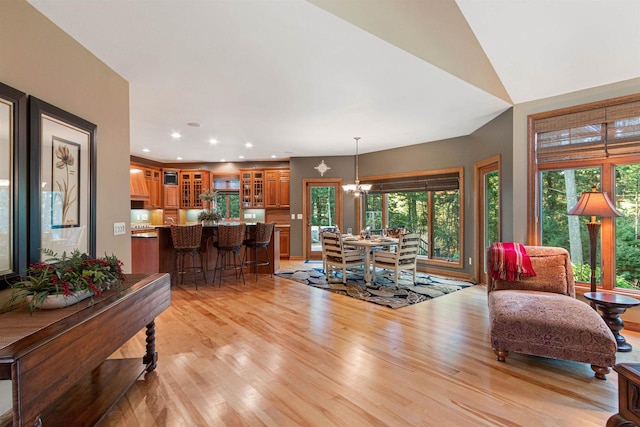 living room featuring lofted ceiling, light hardwood / wood-style flooring, and a chandelier