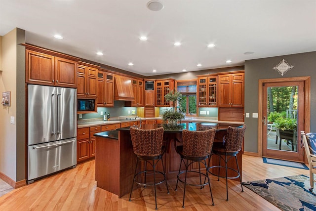 kitchen with black appliances, a healthy amount of sunlight, light wood-type flooring, and a kitchen island