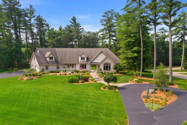 view of front of home with a garage, stone siding, aphalt driveway, and a front yard