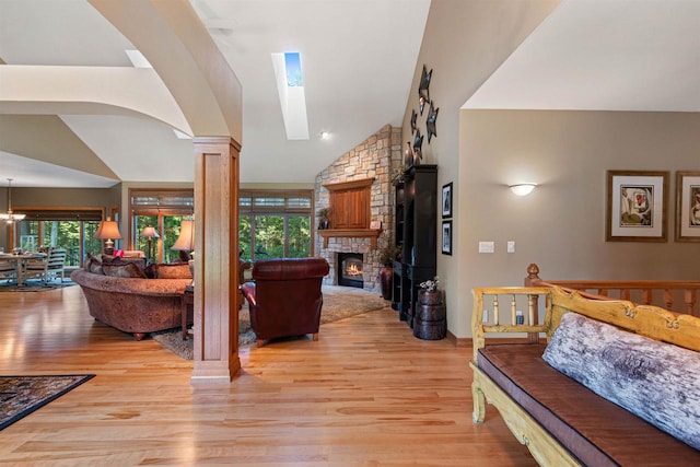 living room featuring light wood-type flooring, high vaulted ceiling, plenty of natural light, and a stone fireplace