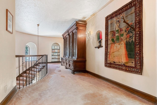 corridor with carpet flooring, an inviting chandelier, and a textured ceiling