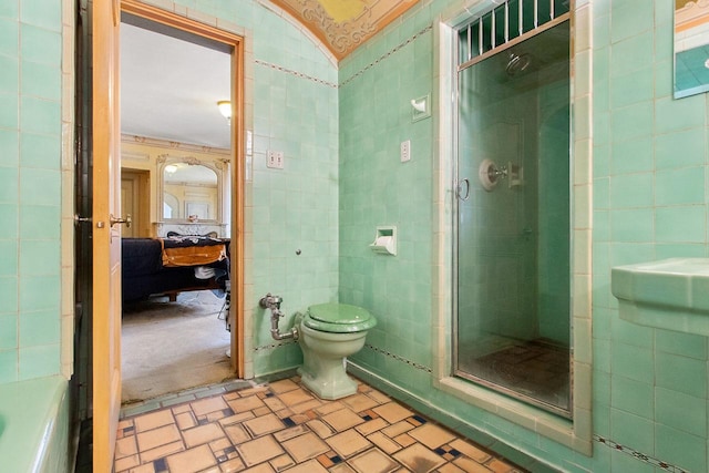 bathroom with tile walls, toilet, and a shower with door