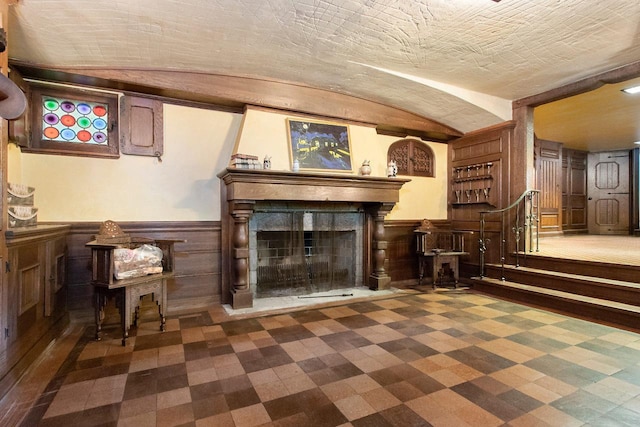 unfurnished living room with dark colored carpet and wood walls