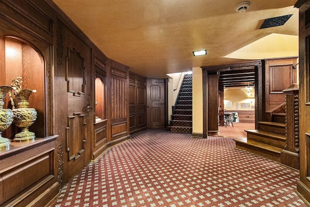 interior space with dark colored carpet and wooden walls