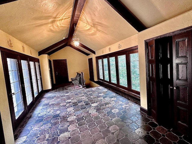 foyer entrance with french doors, lofted ceiling with beams, and a textured ceiling