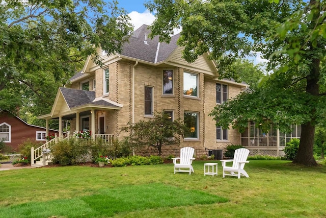 rear view of house with covered porch, central AC unit, and a lawn