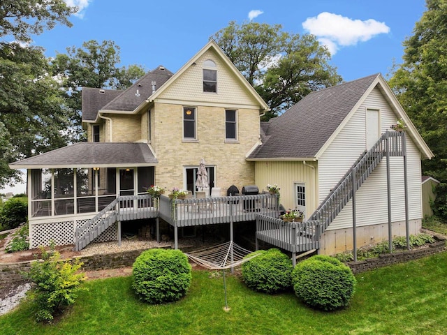 rear view of house featuring a sunroom, a wooden deck, and a lawn