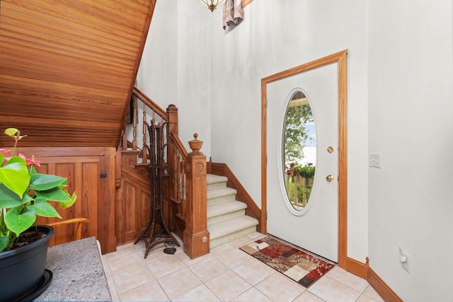 foyer entrance with vaulted ceiling, light tile patterned floors, and wooden ceiling