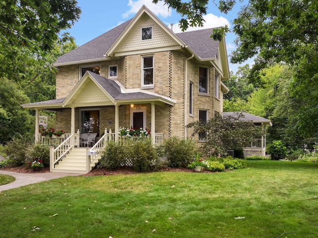 victorian house featuring covered porch and a front yard