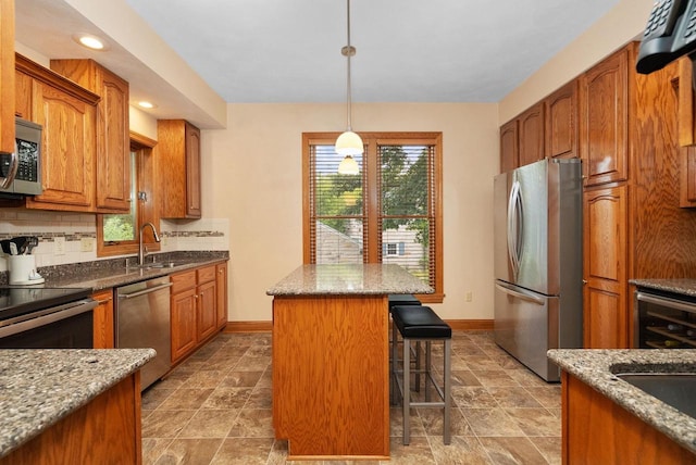 kitchen with a breakfast bar, a center island, appliances with stainless steel finishes, tasteful backsplash, and light stone counters